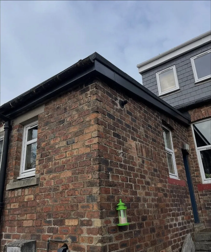 New black fascia, soffit and guttering on a brick building with a slate dormer behind