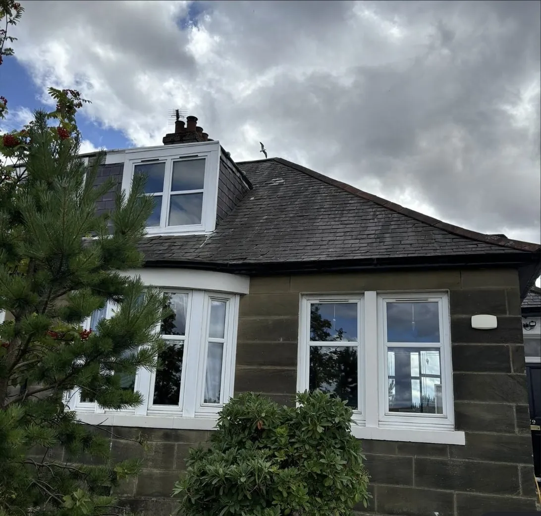 A stone bungalow with a slate roof, dormer and chimney